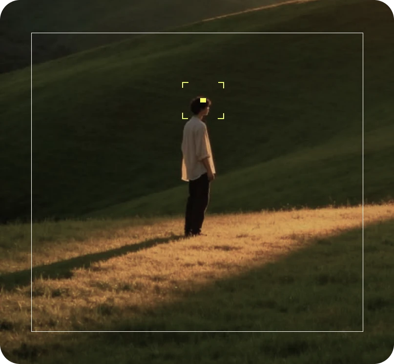 A person standing on a sunlit hillside, framed by the camera